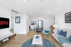A modern living room with a flat-screen TV, a coffee table, and a sofa. - Ocean & River Views | Sauna + Steam Rm (Surfers Paradise)