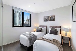 A hotel room with two beds, a large window with a city view, and a framed artwork on the wall. - Ocean & River Views | Sauna + Steam Rm (Surfers Paradise)