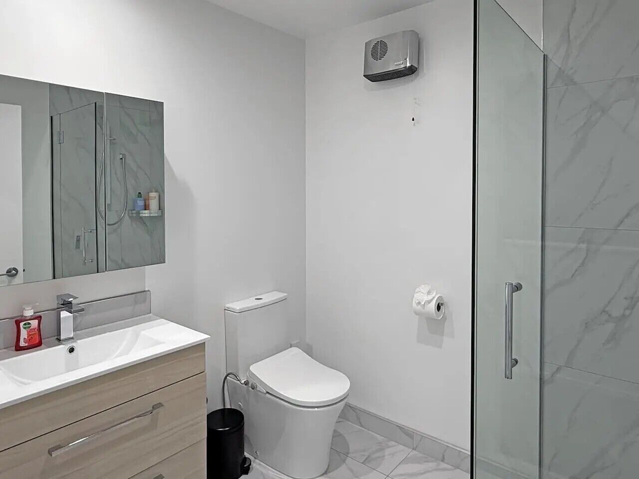 Ein modernes Badezimmer mit Duschkabine aus Glas, Toilette und Waschtisch mit Spiegel.