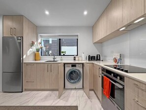 A modern kitchen with a built-in washing machine, a refrigerator, and a stove.
