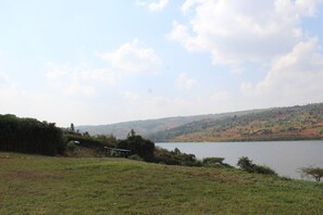 A grassy area with a lake and hills in the background.