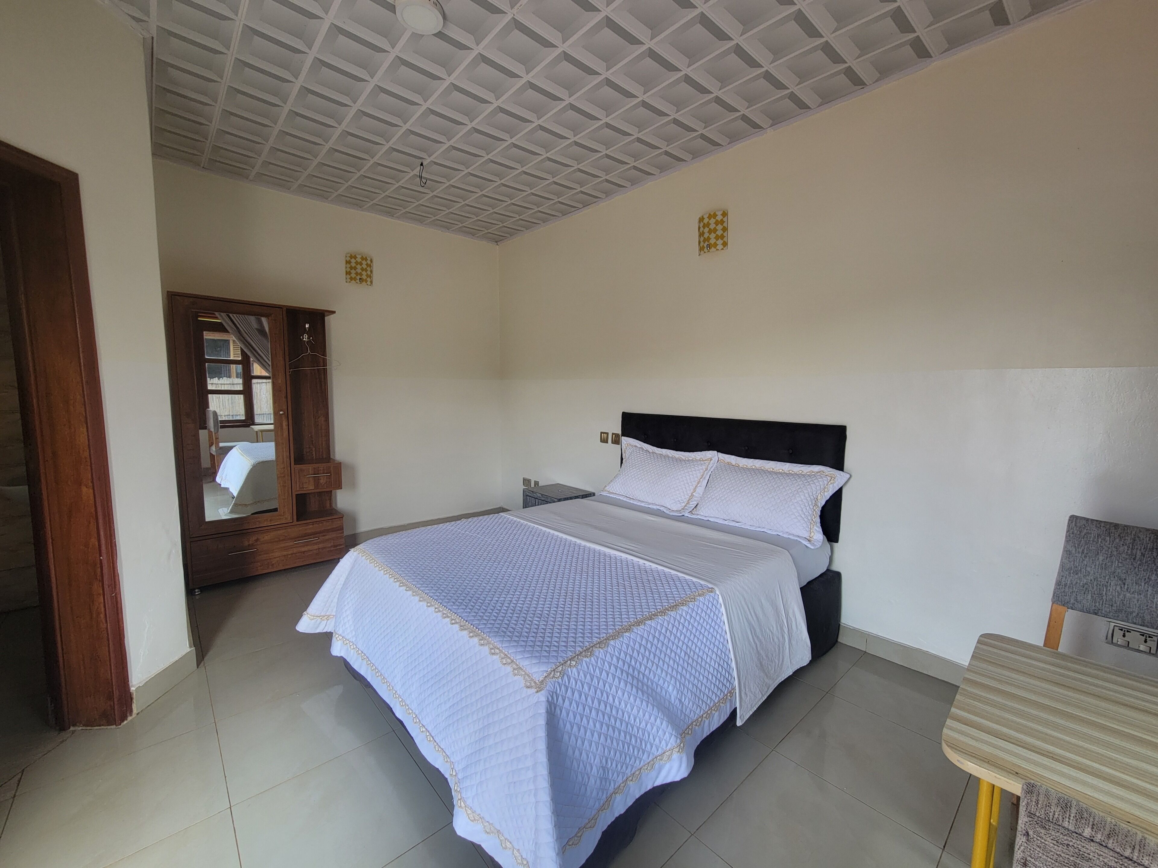 Un dormitorio con cama, armario de madera, espejo y una mesita.