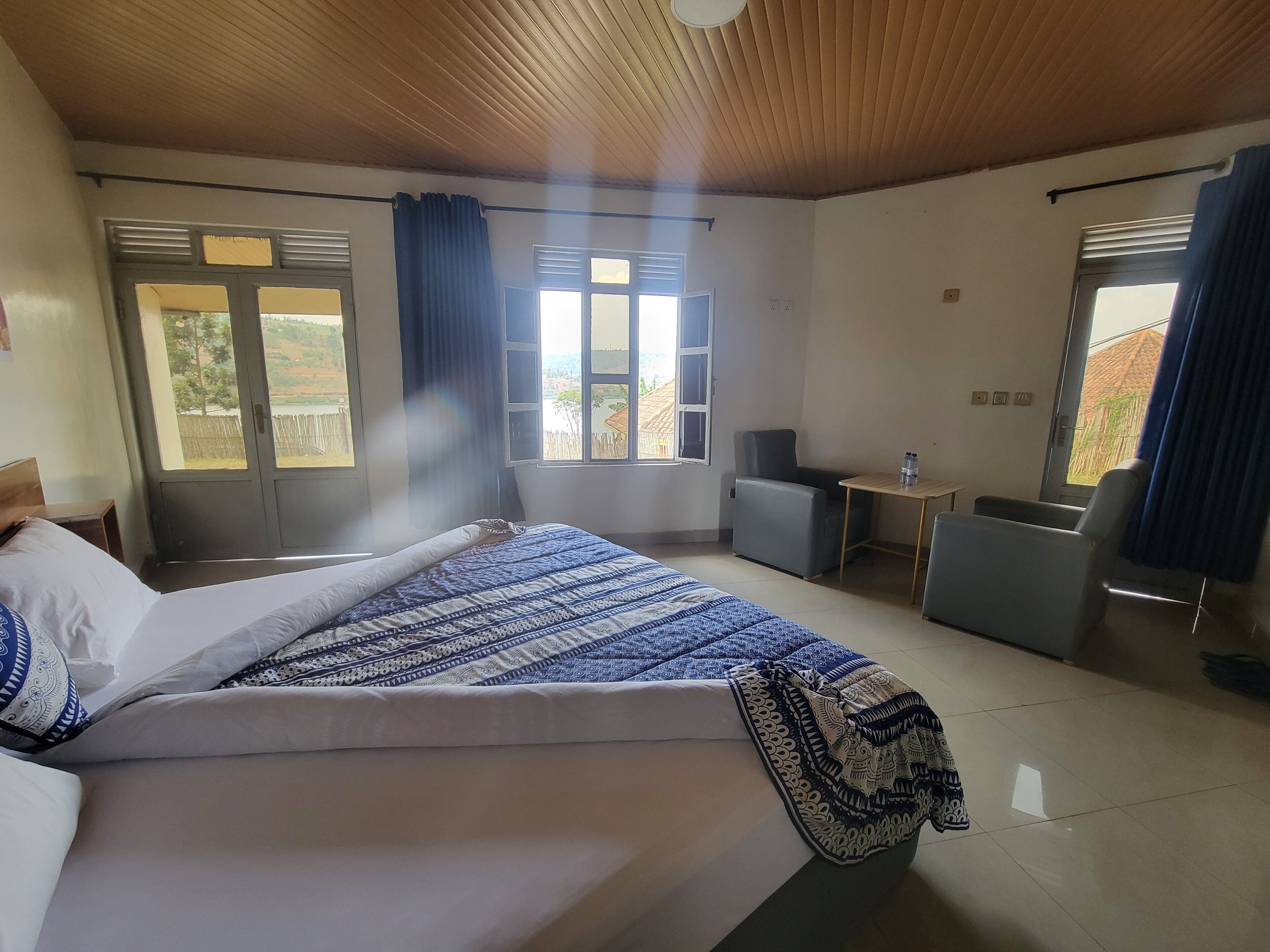 A hotel room with a bed, a desk, a chair, and a window with curtains.
