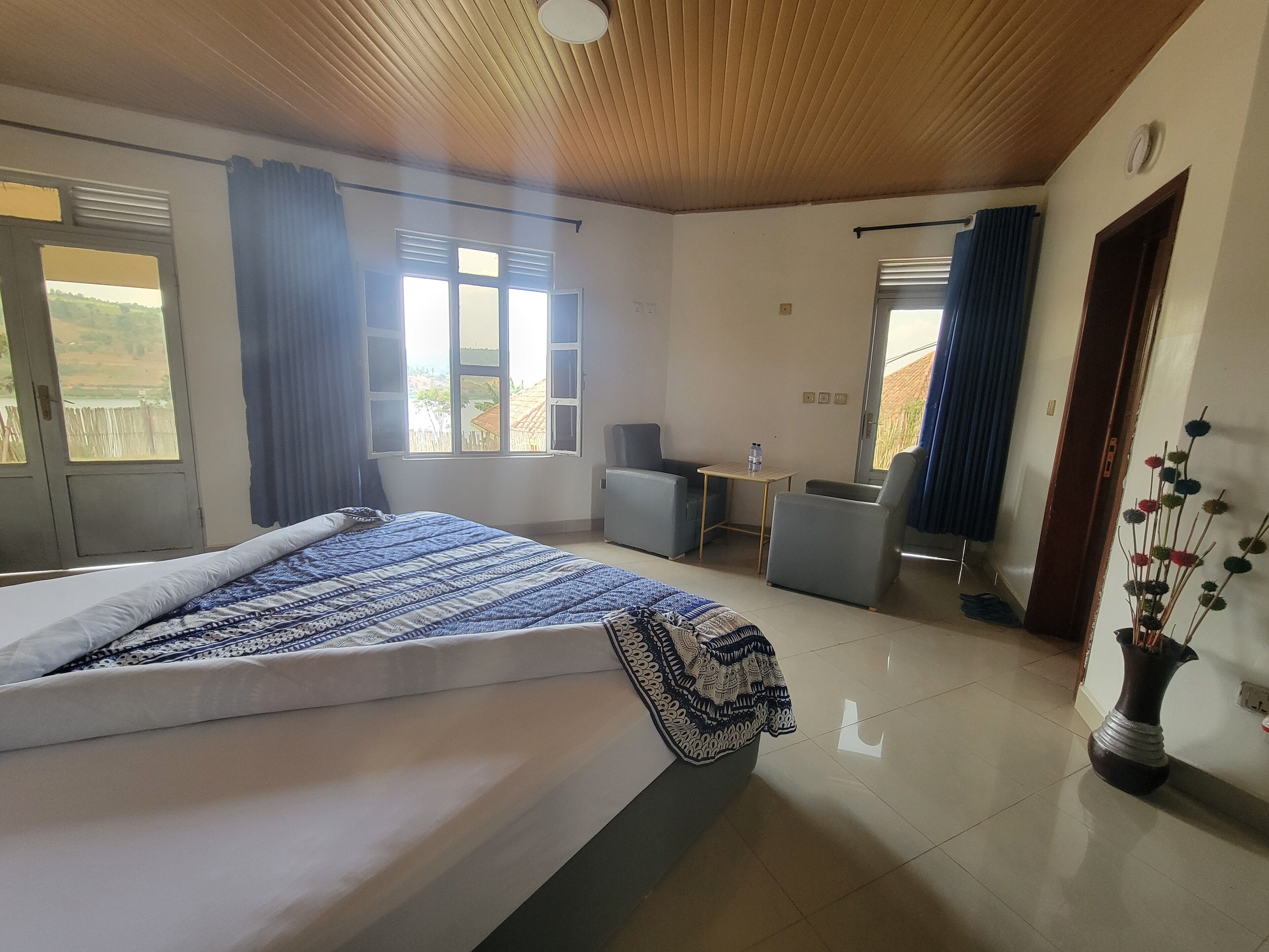 Ein Hotelzimmer mit Bett, Schreibtisch, zwei Stühlen und Blick ins Freie.
