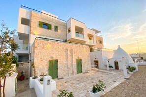 A modern building with a stone facade, multiple balconies, and a courtyard with potted plants. - ALL BlueNote – 2 Bedrooms, 2 Baths & Stunning Sea Views (Polignano a Mare)