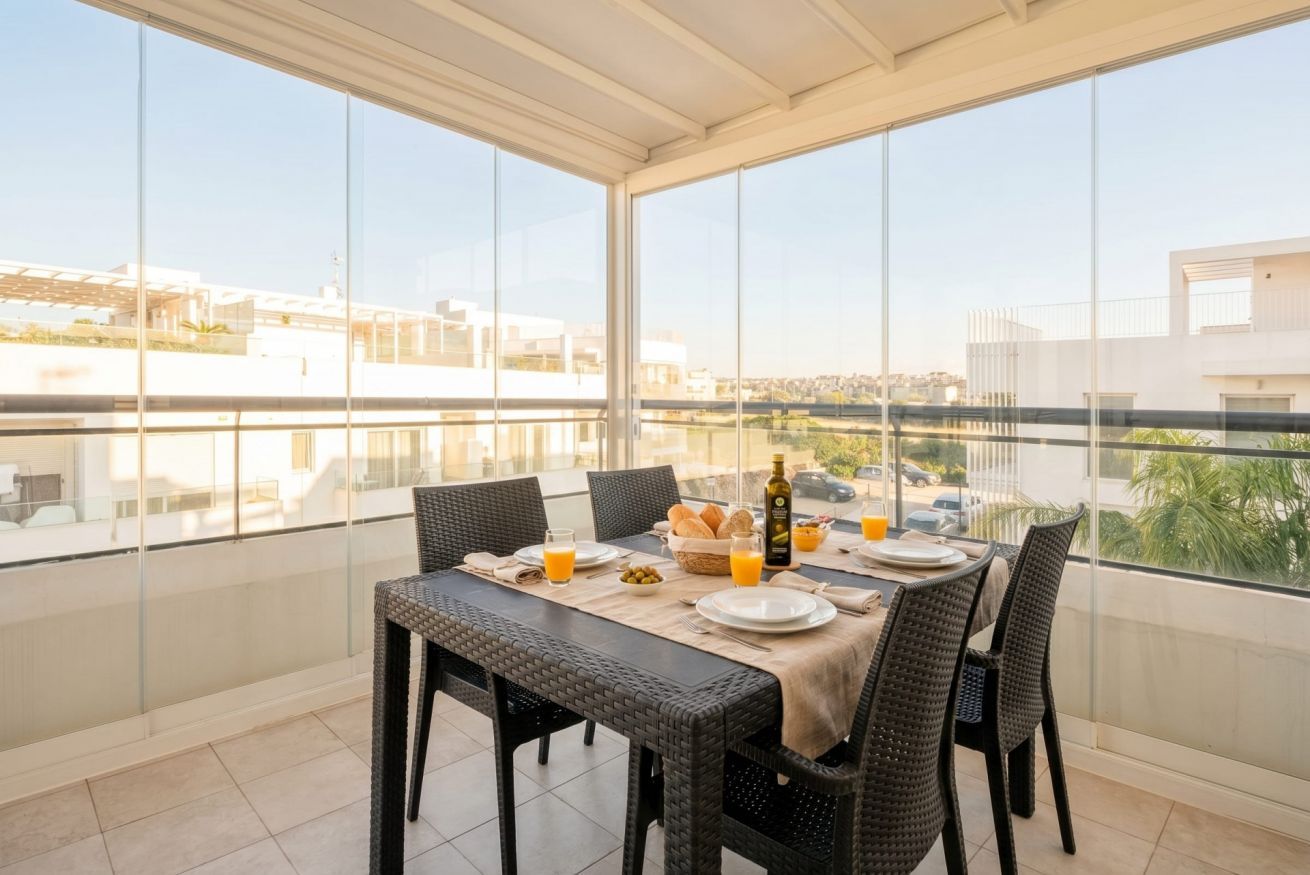A balcony with a table set for breakfast, overlooking a cityscape.