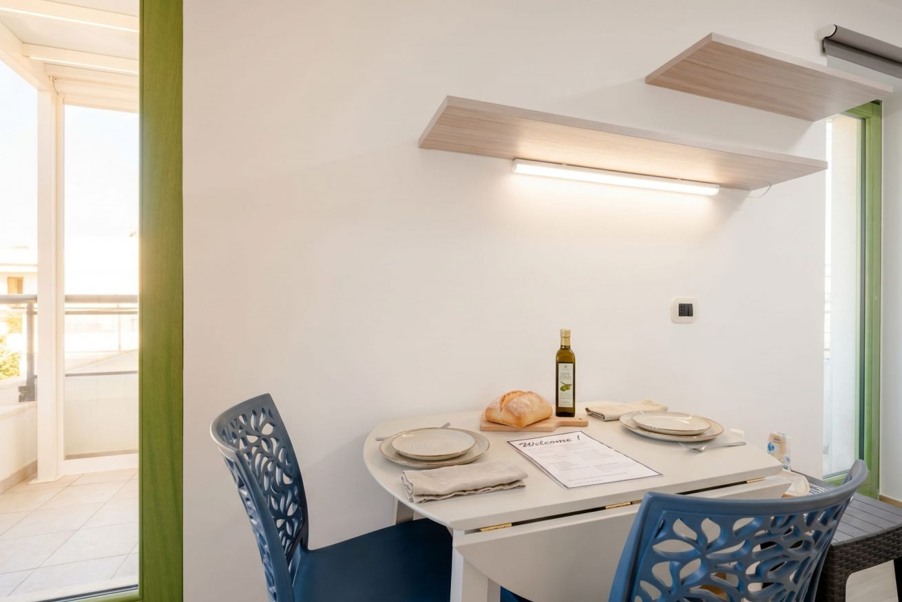 A dining area with a table set for two, a bottle of wine, and a menu.