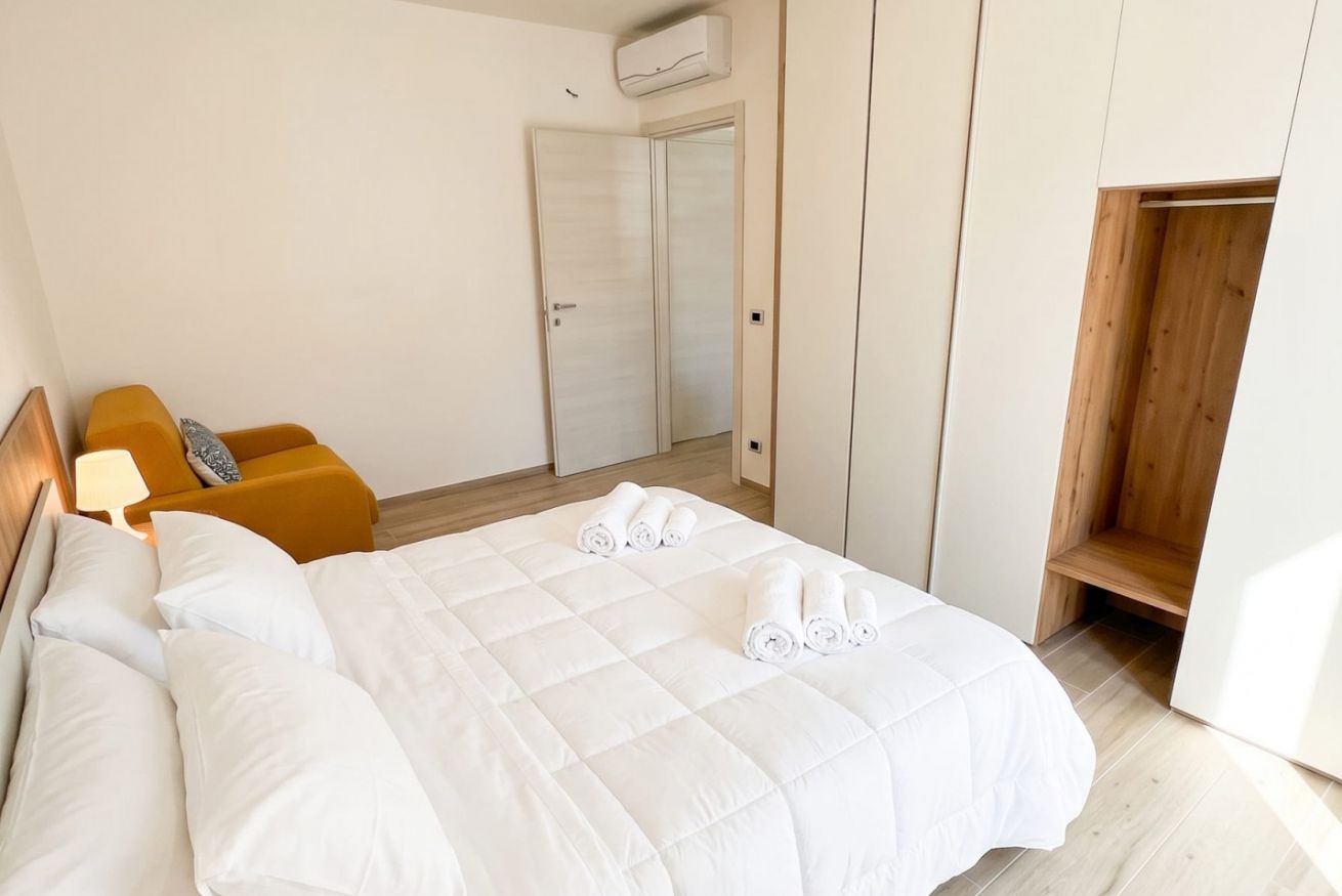 Habitació d'hotel amb un llit, una banca de fusta, un armari i una porta.