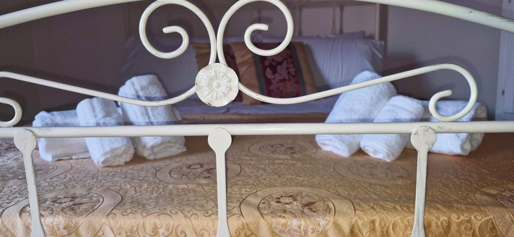 Un letto con struttura metallica e copripiumino decorato.