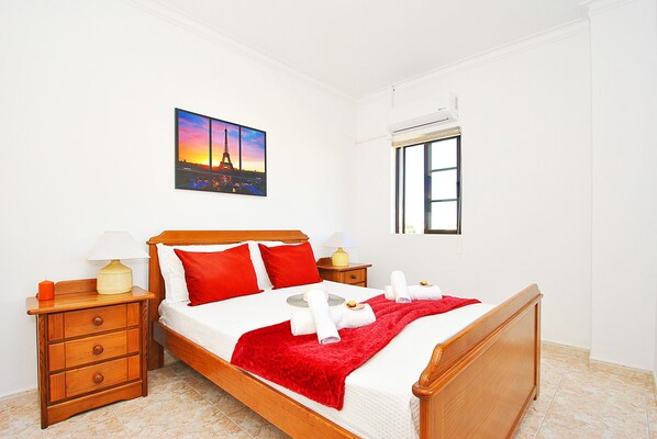 A hotel room with a bed, a nightstand, a drawer, a window, and a picture of the Eiffel Tower.