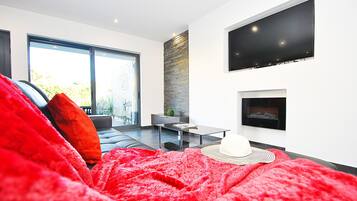 Una sala de estar moderna con un ventanal grande, chimenea y televisor de pantalla plana montado en la pared.