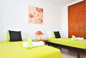 A hotel room with two beds, a small table with a lamp, and a wooden wardrobe. - Family villa with BBQ and heatable pool (Albufeira)
