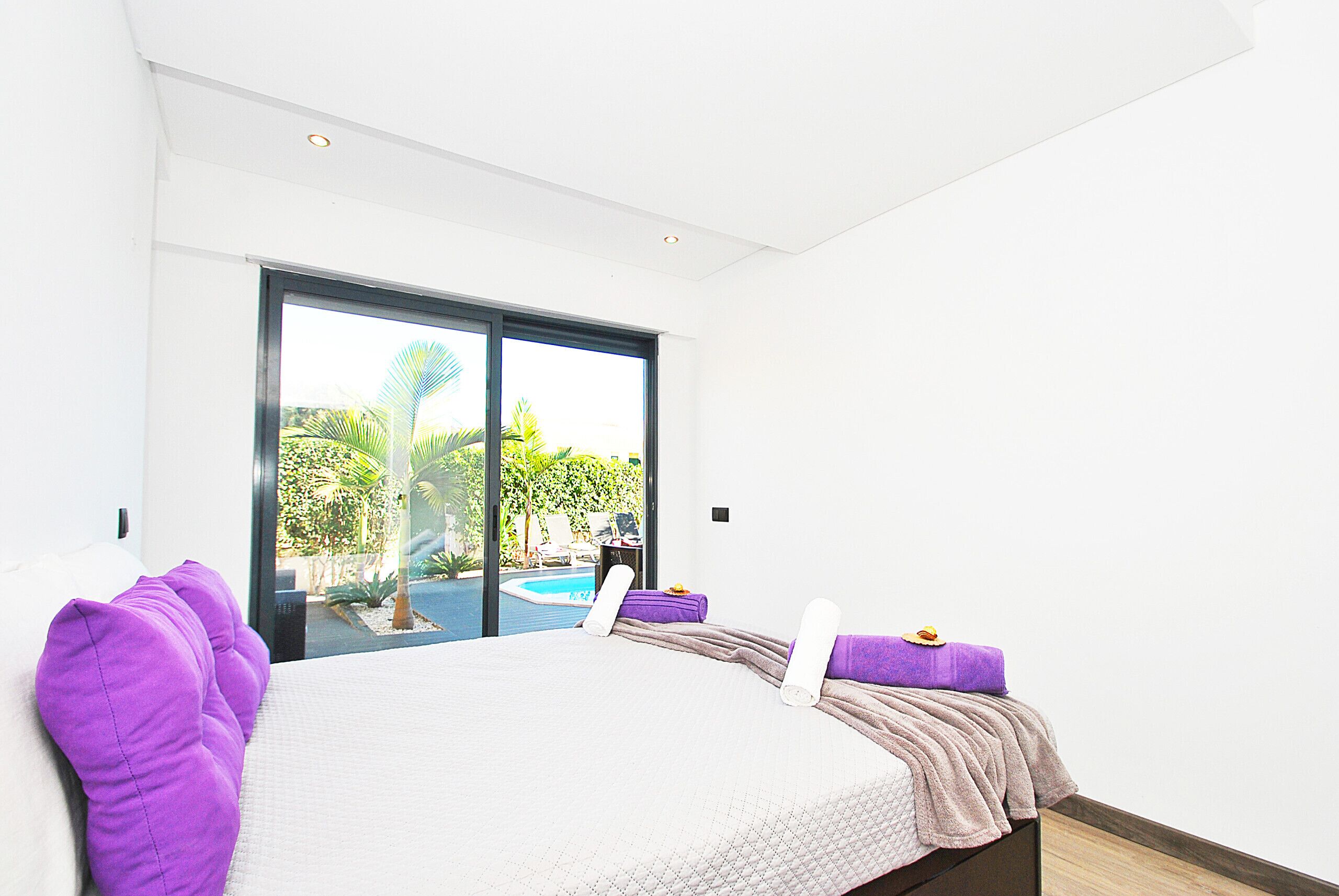 Un dormitorio con cama, vista a una piscina y puerta que da a un espacio exterior.