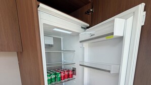 Ein kompakter Kühlschrank mit Frischefach, einem Gefrierfach und Einlegeböden für Getränke.