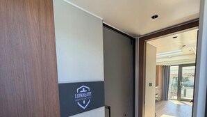 Ein Hotelkorridor mit einer Schiebetür, einem Logo an der Wand und Blick ins Freie.