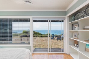 Ein Zimmer mit einer großen Schiebeglasdoor, die auf eine Terrasse mit Meerblick führt.