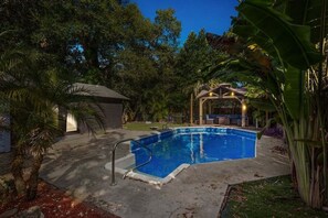 A swimming pool surrounded by trees and a covered patio area. - Private Pool + Guesthouse & Arcade | Tampa (Tampa)
