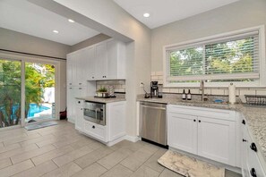A modern kitchen with white cabinetry, a built-in oven, and a dishwasher. - Private Pool + Guesthouse & Arcade | Tampa (Tampa)