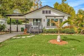 A single-story house with a covered porch, a small garden, and a palm tree. - Private Pool + Guesthouse & Arcade | Tampa (Tampa)