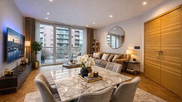 A modern living room with a dining area, large windows, and a view of a cityscape.