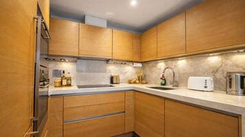 A modern kitchen with wooden cabinets, a marble countertop, and stainless steel appliances.