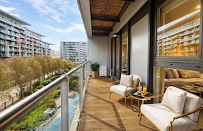 Ein Balkon mit Holzboden, einer Couch, einem Sessel und einem Tisch mit einem Tablett Orangensaft.