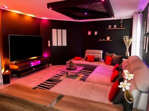 Ein modernes Wohnzimmer mit Flachbildfernseher, einer Couch, einem Couchtisch und einer dekorativen Vase mit Blumen.