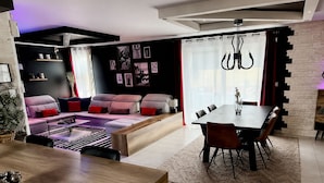 A modern living room with a sofa, dining table, and chairs. - Must-See / Jacuzzi - Pool - Sauna - Turkish Bath (Challans)
