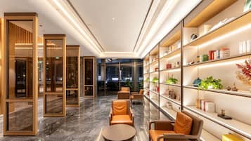 Um lobby moderno com piso de mármore, área de estar e uma estante com diversos objetos.
