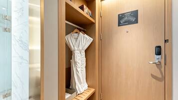 A wooden wardrobe with a robe hanging inside, a shelf with books, and a door with a lock and a sign.