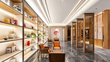 A modern interior with a long hallway, bookshelves, seating area, and a circular decorative element on the wall.