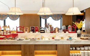A hotel buffet with a marble countertop, multiple serving stations, and a variety of food and drink options.