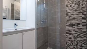 A modern bathroom with a shower, a sink, and a mirror.