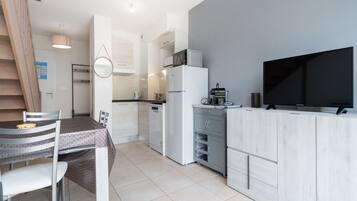A modern kitchen with a flat-screen TV, a microwave, and a refrigerator.