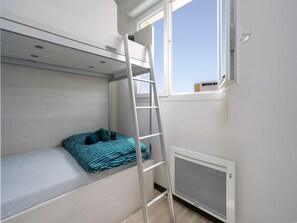 A bunk bed with a ladder, a window, and a radiator. - Seaside Comfort in Valras (Sérignan)