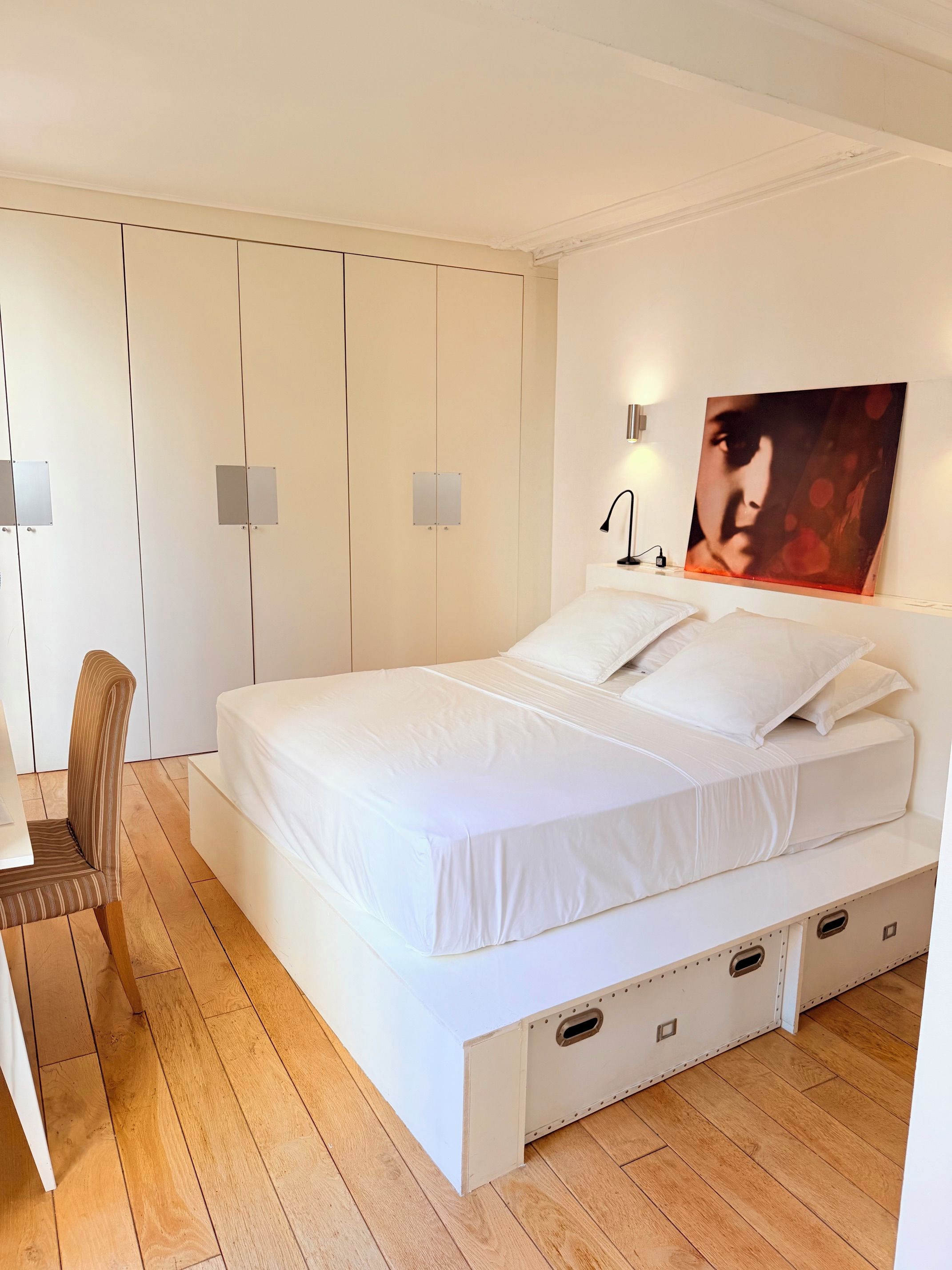 Ein Schlafzimmer mit Bett, Sessel, Schreibtisch und Kleiderschrank.