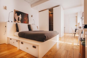 Un dormitorio moderno con cama empotrada, un ventanal grande y un armario.