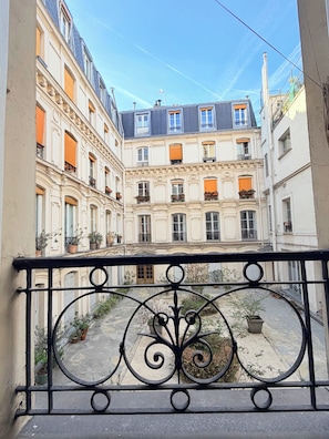A courtyard with buildings on either side, featuring balconies with potted plants. - Quiet And Airy Luxury Studio In The Upper Marais (Paris)