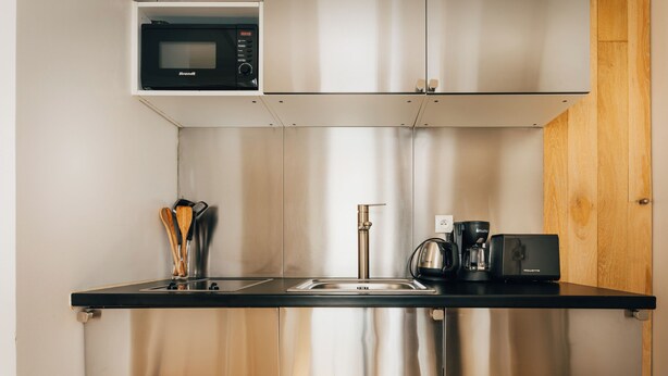 Eine kompakte Küche mit Edelstahl-Spüle, Kaffeemaschine und Mikrowelle.