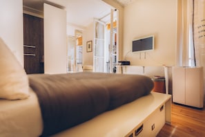 Un dormitorio con cama, televisor montado en la pared y armario.