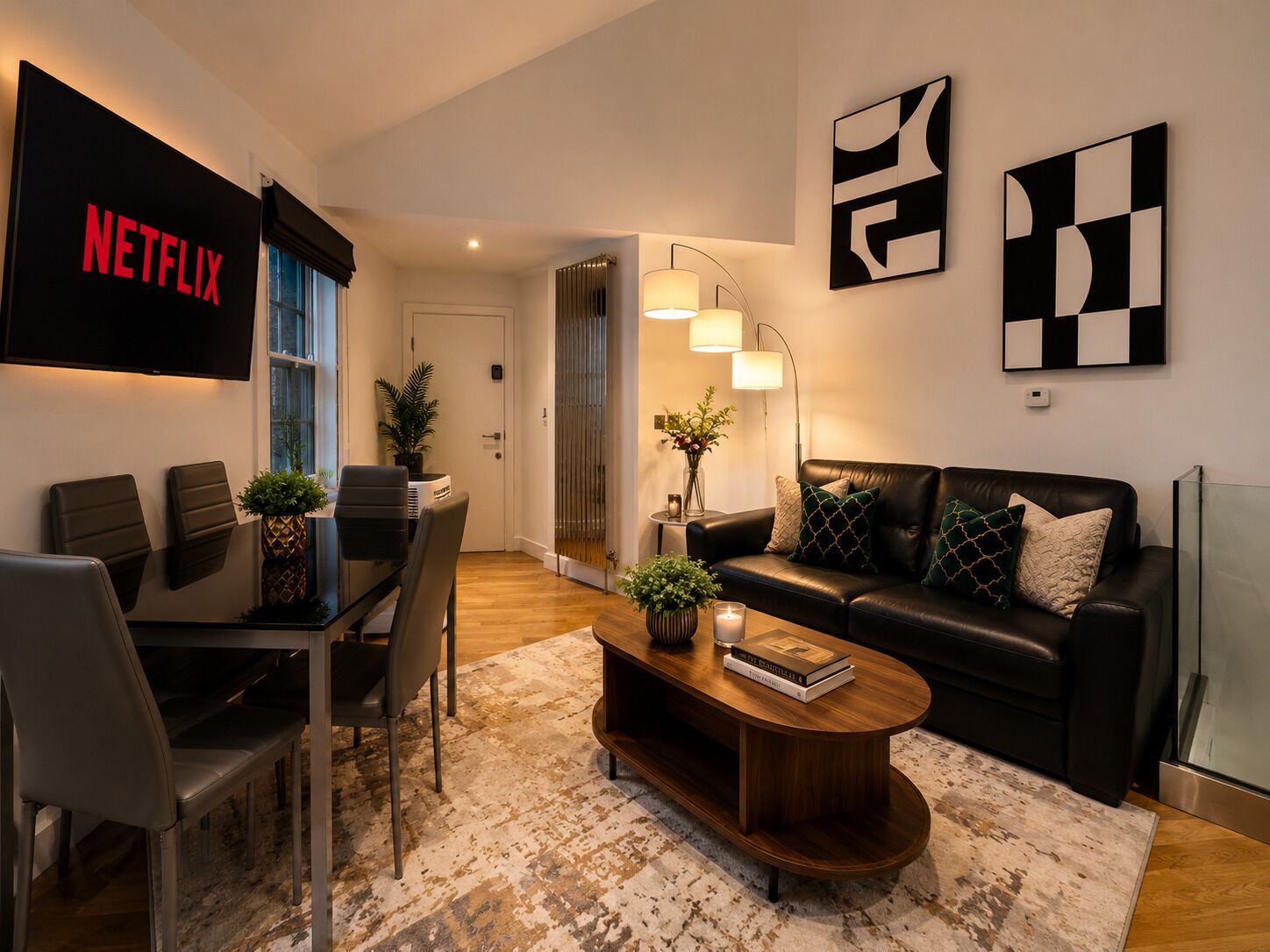 Un salon moderne avec un canapé en cuir noir, une table basse et un téléviseur fixé au mur.