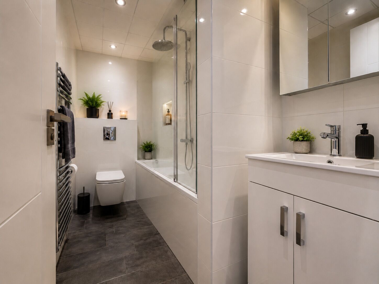 Une salle de bain moderne avec une douche à parois de verre, des toilettes blanches et un meuble-lavabo avec un miroir.
