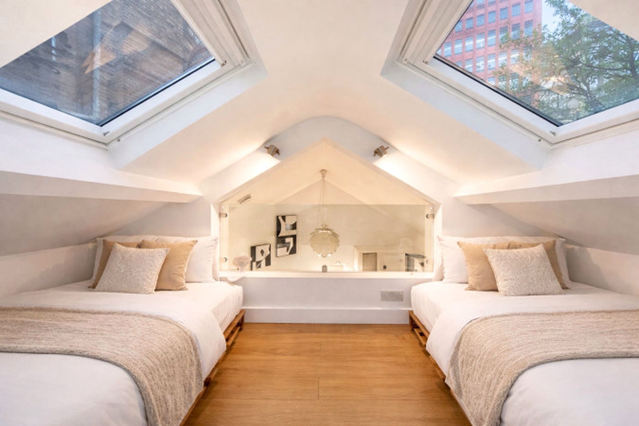 Une chambre avec deux lits, une lucarne et une vue sur la ville.