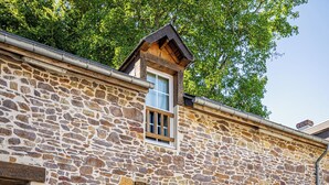 Edificio de piedra con terraza y cartel que dice 'Gîte de campagne'.