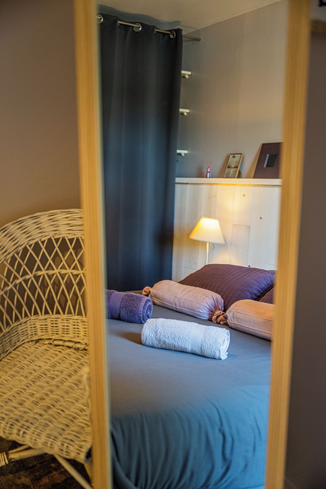 Une pièce comprenant un lit, une chaise, une lampe et un miroir.
