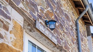 Un edificio de piedra con un letrero que dice 'Gîte de la cour' y una ventana.