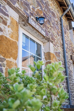 A stone building with a sign reading 'Gîte de la cour' and a window.