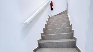 A staircase with a handrail and a fire extinguisher mounted on the wall. - Caletillas BlackSand—ocean views—Wi-Fi—garage—2 bedrooms, pool. (Candelaria)