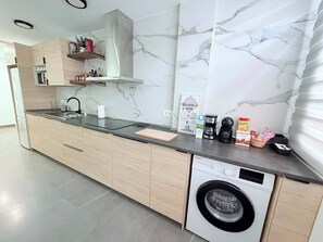 Eine moderne Küche mit eingebauter Waschmaschine, Marmor-Spritzschutz und Holzschränken.