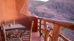 Un área de estar al aire libre de estilo rústico con una mesa y sillas, con vistas a un paisaje montañoso.